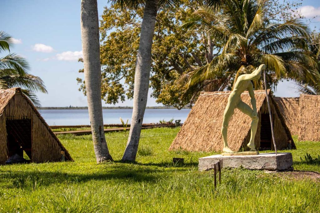 Taíno village at Zapata National Park – Photo: Shutterstock statue and small huts with thatched roofs on grass lawn