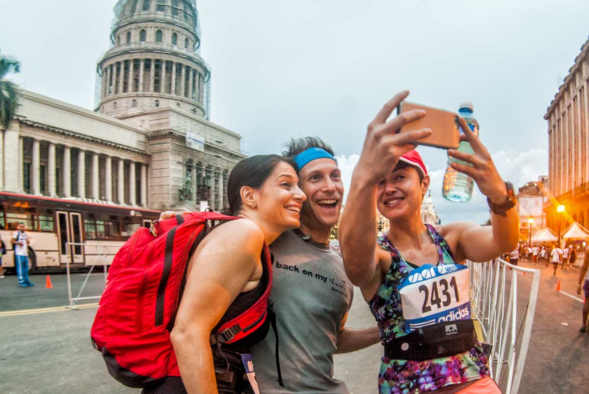 Runners taking a selfie at Marabana, Havana Marathon – Photo: Shutterstock three people taking a selfie in front of a parliament building