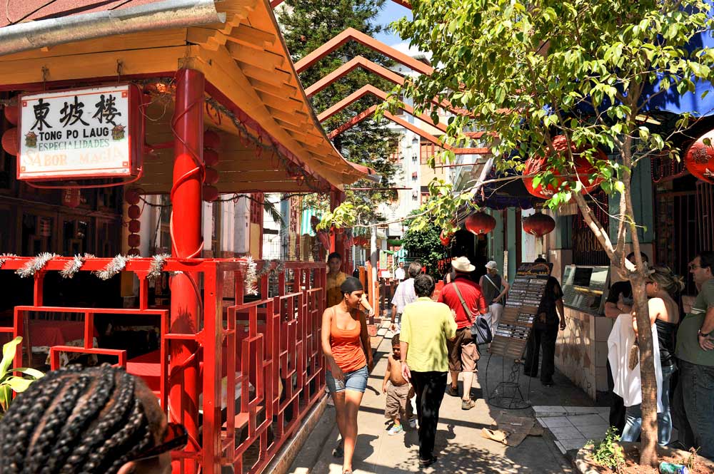 narrow street with chinese signs and lamps hanging in trees