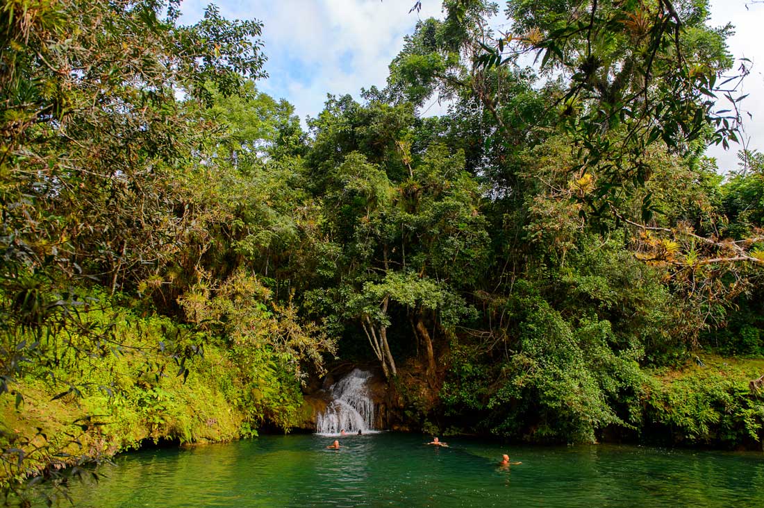 Waterfall and natural pool, Topes de Collantes – Photo: Shutterstock people swimming in a water pond with waterfall surrounded by forest